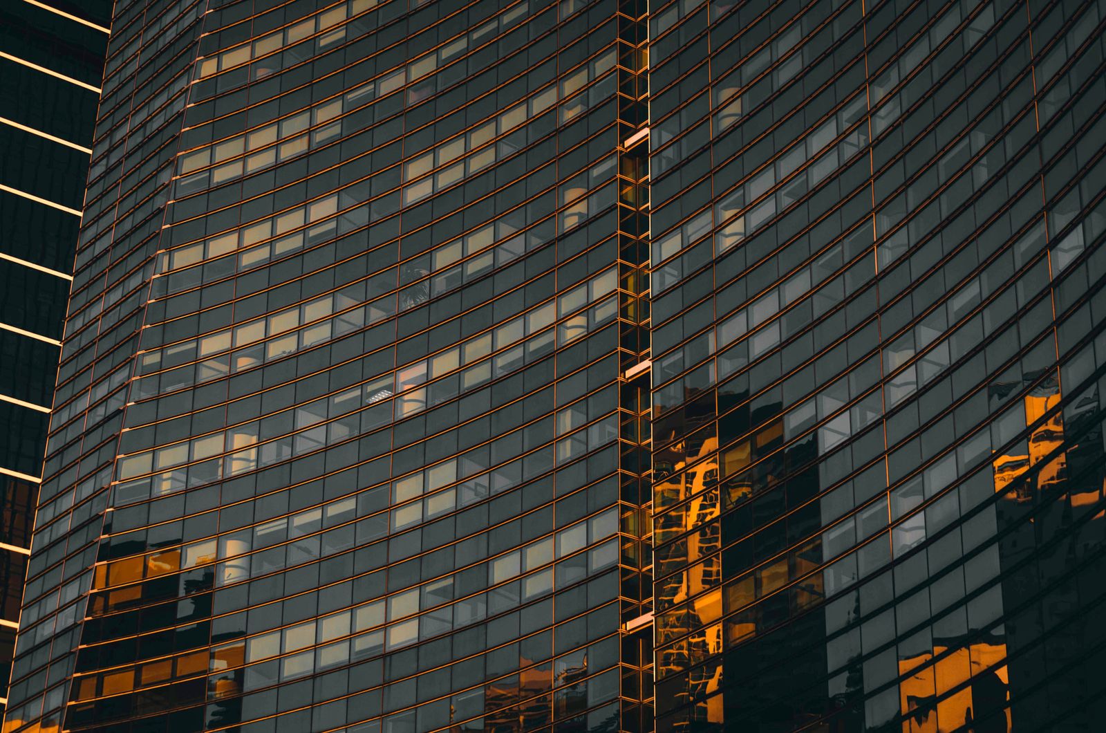A curved glass facade catching amber reflections